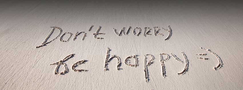 “Don’t worry be happy” message written in beach sand, symbolizing physical comfort and emotional lightness associated with bodily balance.